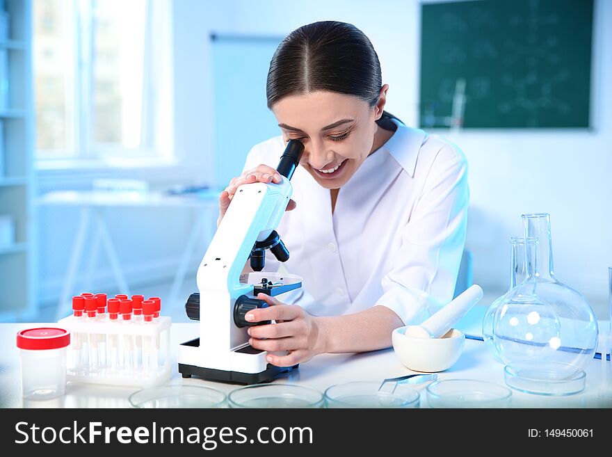 Female scientist using modern microscope in laboratory