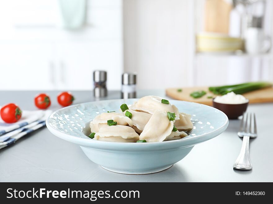 Plate of tasty dumplings served with green onion on table