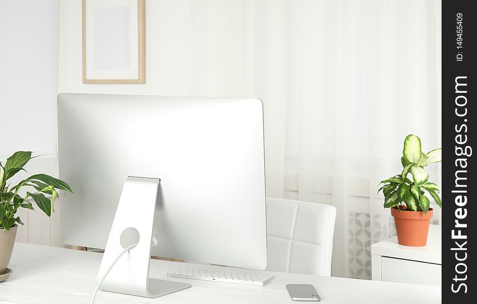 Office interior with houseplants and computer monitor on table