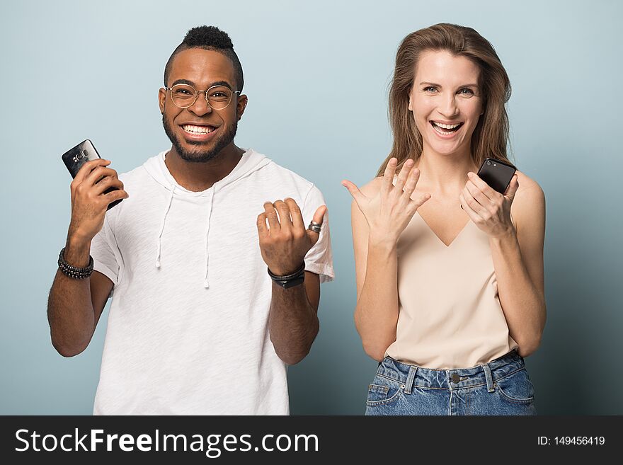 Surprised multiracial diverse people isolated on blue studio background hold smartphones look at camera amazed by unexpected news, multiethnic man and woman feel shocked using cellphones. Surprised multiracial diverse people isolated on blue studio background hold smartphones look at camera amazed by unexpected news, multiethnic man and woman feel shocked using cellphones