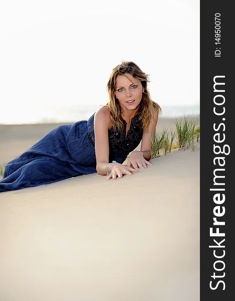 Beautiful fashion woman sitting on the beach in a sand and smiling. Beautiful fashion woman sitting on the beach in a sand and smiling