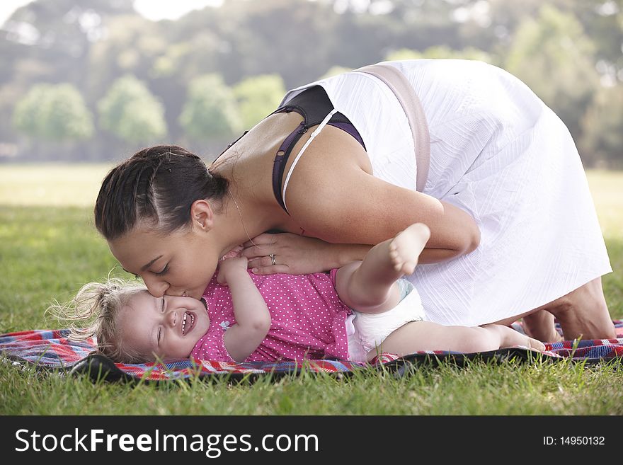 Mother playing and kissing with daughter in the park in summer. Mother playing and kissing with daughter in the park in summer