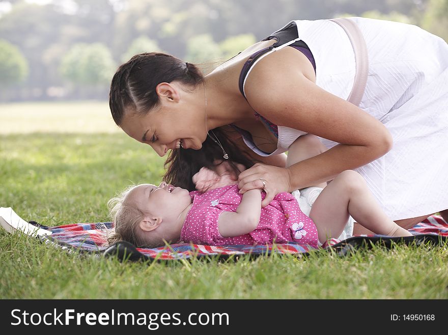 Mother playing with daughter in the park in summer
