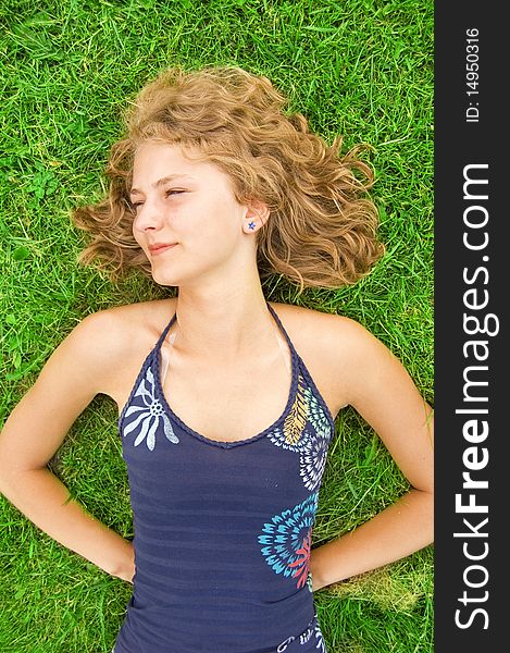 Vacation conceptual image. Young teenage girl lying on grass and relaxes.