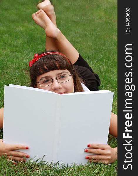 Pretty girl on a grass looking over the book. Pretty girl on a grass looking over the book