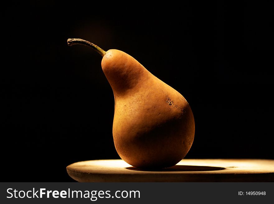 Pear on wood - black background, light painting tecnique.