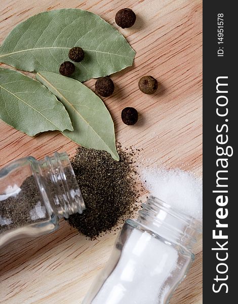 Spices: pepper, salt and bay leaves closeup on wooden background