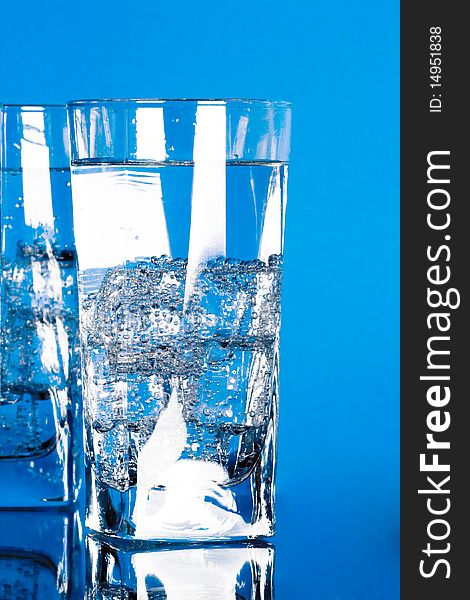 Glasses with cold water on blue background