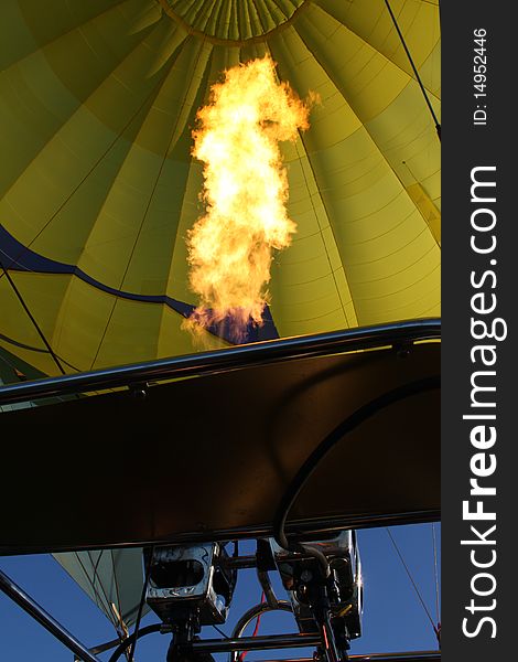 Gas burner flame blowing heat into yellow balloon. Gas burner flame blowing heat into yellow balloon