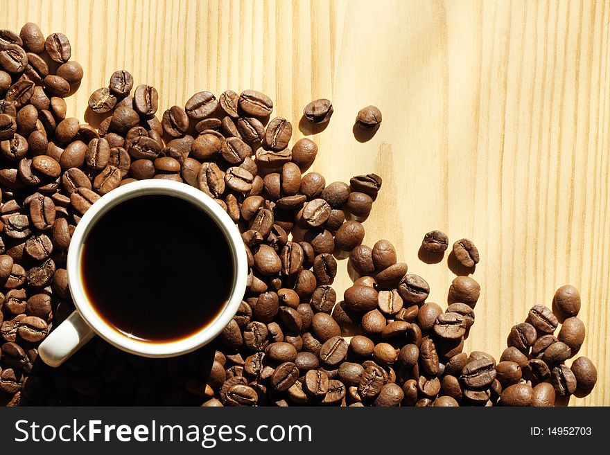 Cup of black coffee and coffee beans on wooden background