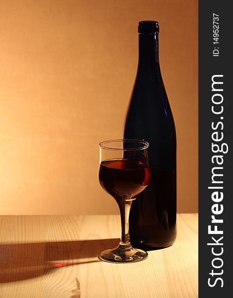 Wineglass near bottle of red wine with reverberation on brown background