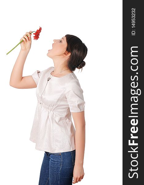 Charming young girl in blue jeans and a white blouse with a red flower in the hands