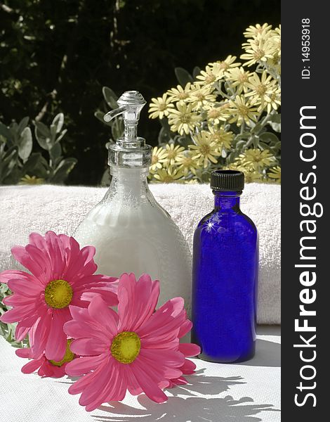 Liquid soap a white towel and silk flowers in a sunny garden