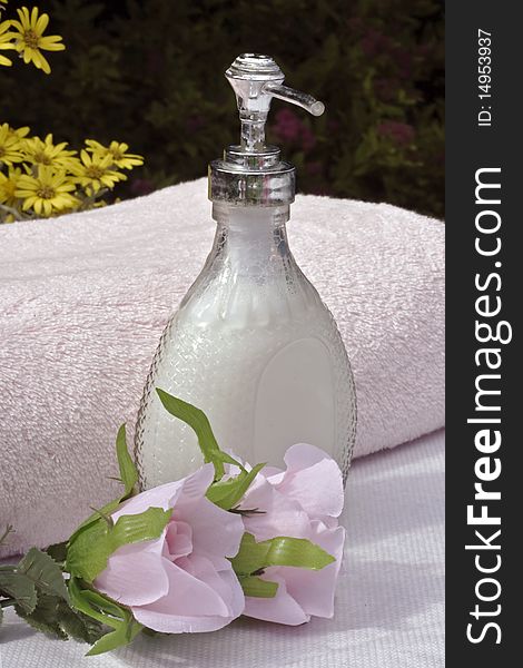 Liquid soap a pink towel and silk flowers in a sunny garden