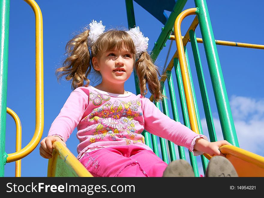 In the summer on a children's playground the child sits on a hill. In the summer on a children's playground the child sits on a hill