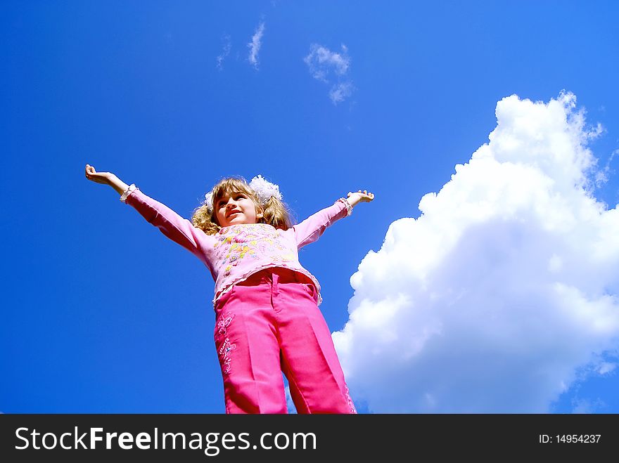 The seven-year girl in pink clothes against the sky has lifted hands upwards. The seven-year girl in pink clothes against the sky has lifted hands upwards