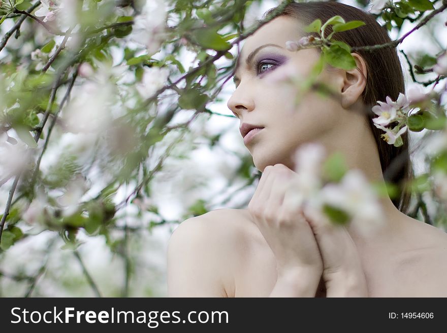 Young girl near blooming apple tree