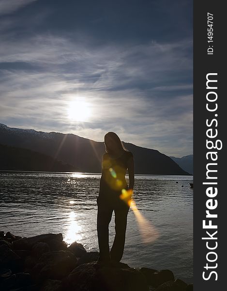 Shot of a woman posing in front of sunset on a fjord