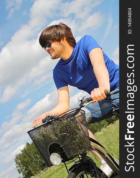 Young handsome man riding a bike in the middle of meadow