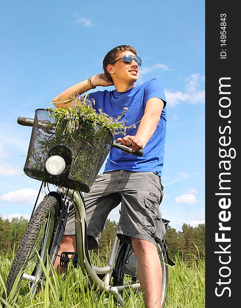 Young handsome man riding a bike in the middle of meadow