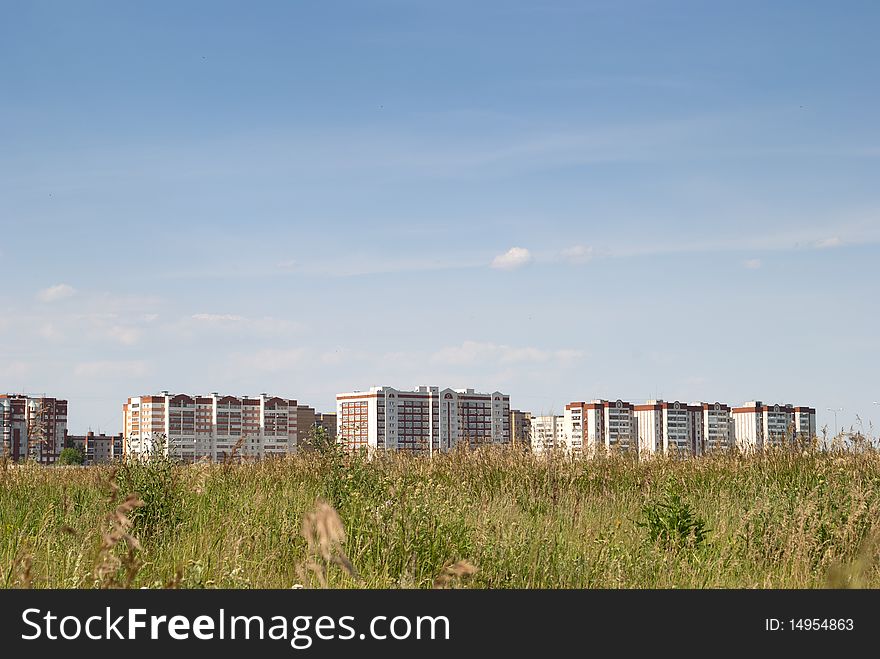 Appartment buildings against the blue sky and green field