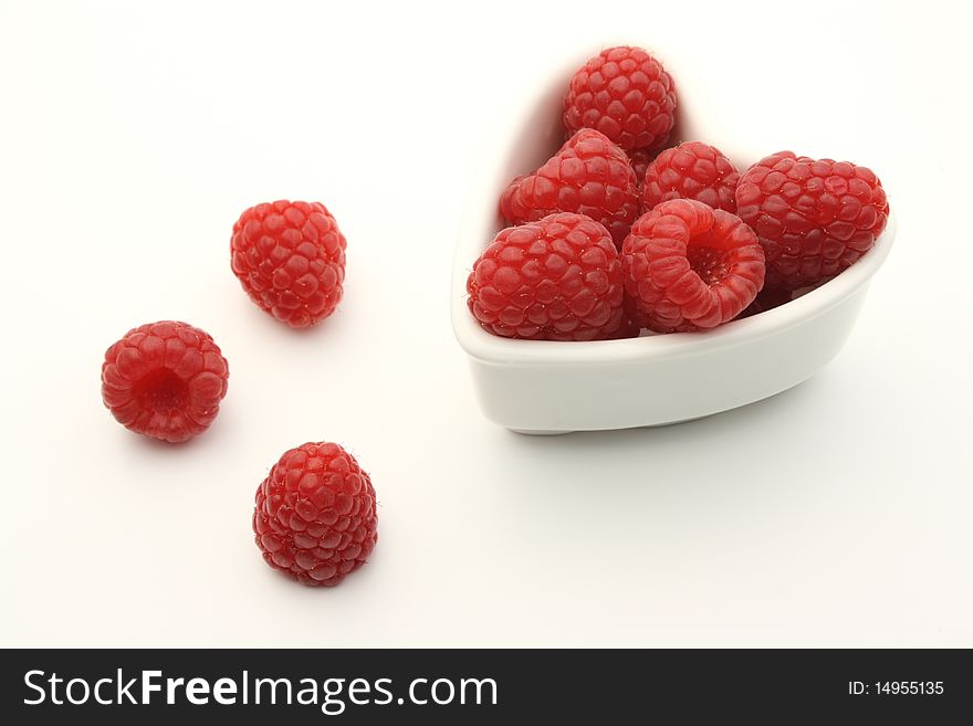 Fresh raspberries in a heart shaped white bowl