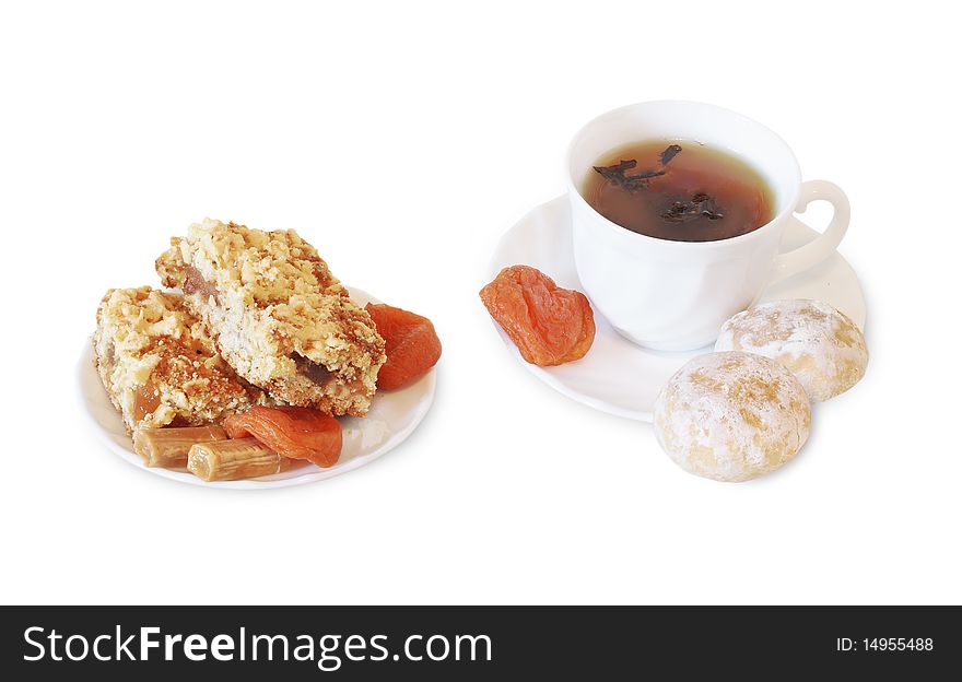 White cup of hot black tea and honey cake on the right side and apple pie, toffee, dried apricots on white plate on the left side. Isolated white background. White cup of hot black tea and honey cake on the right side and apple pie, toffee, dried apricots on white plate on the left side. Isolated white background