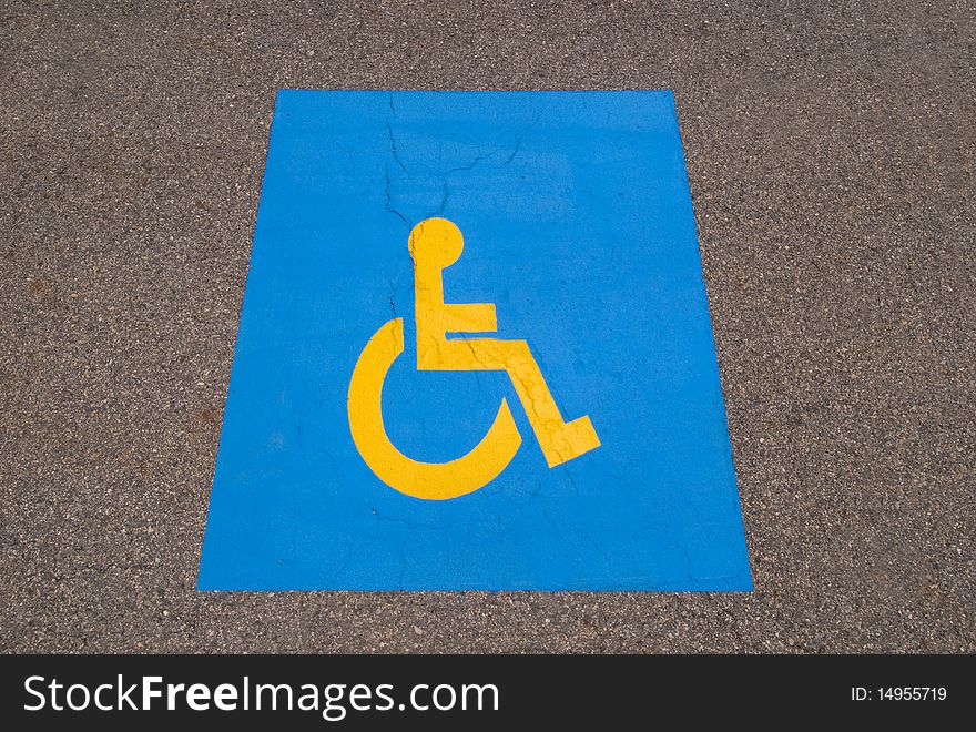 Handicap symbol painted on black asphalt parking lot
