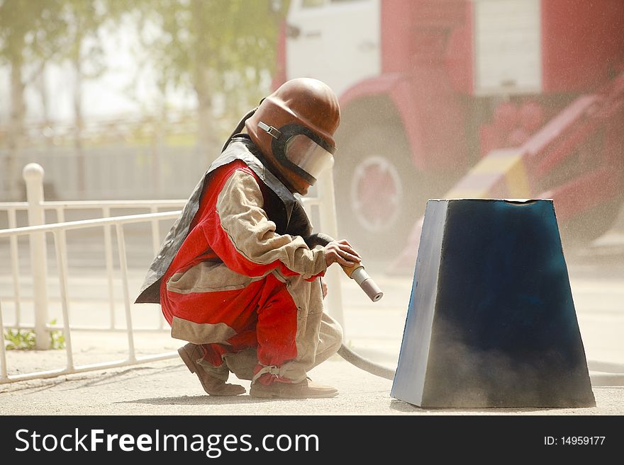 Worker in a protective suit spraying sand