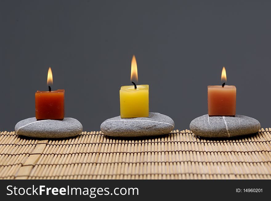 Colorful alight candle on row of stones. Colorful alight candle on row of stones