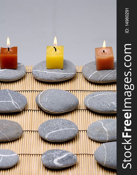 Colorful alight candle on row of stones