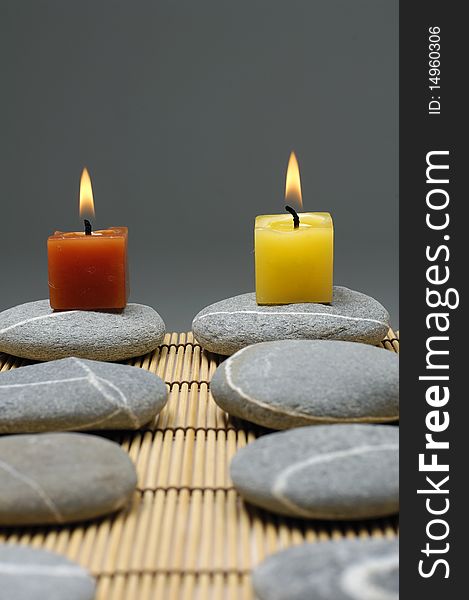 Row of colorful alight candle on zen stones. Row of colorful alight candle on zen stones