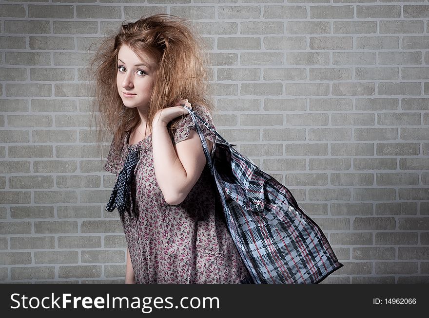 Tired redhaired woman with shopping bag.  brick wall as background.