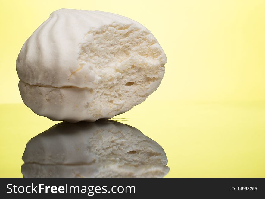Bitten white marshmallow on reflective surface