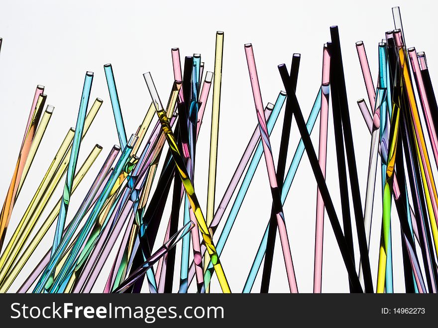 Glass straws with colored liquid on white