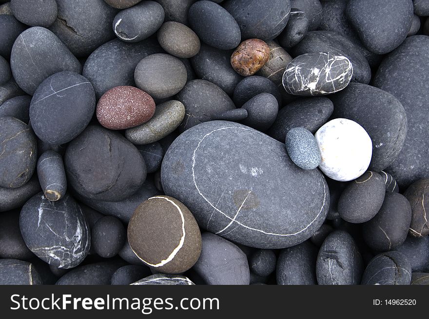 Pebbles of different shapes and colours on a beach. Pebbles of different shapes and colours on a beach