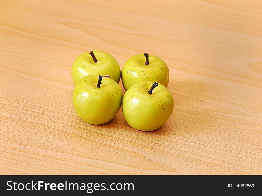 Four green apples on a wooden background
