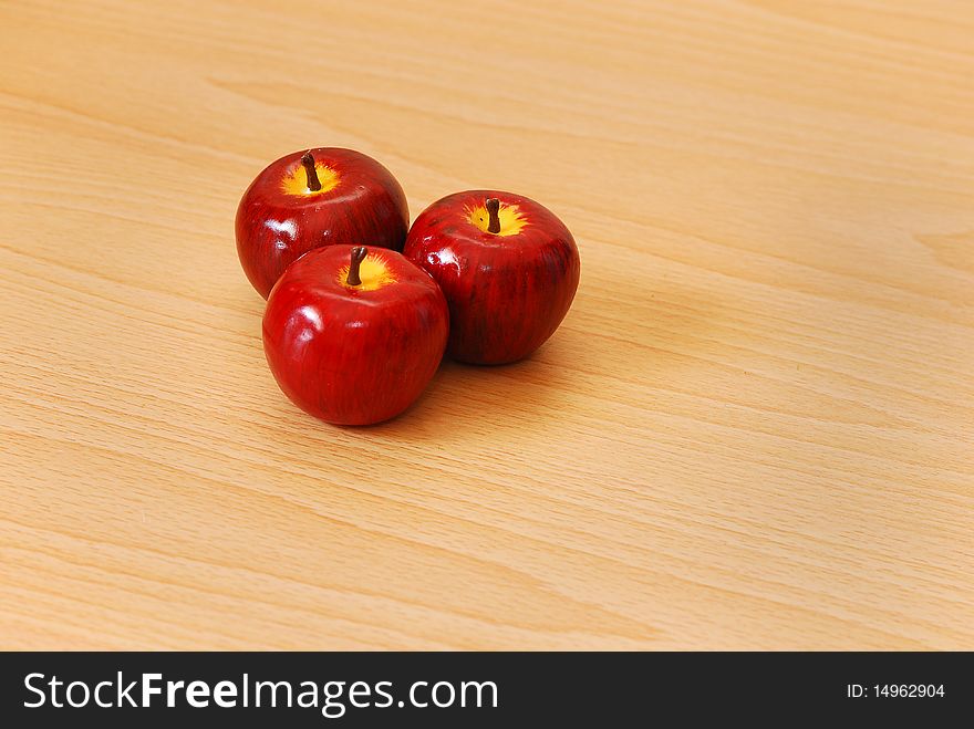 Three red apples on a wooden background