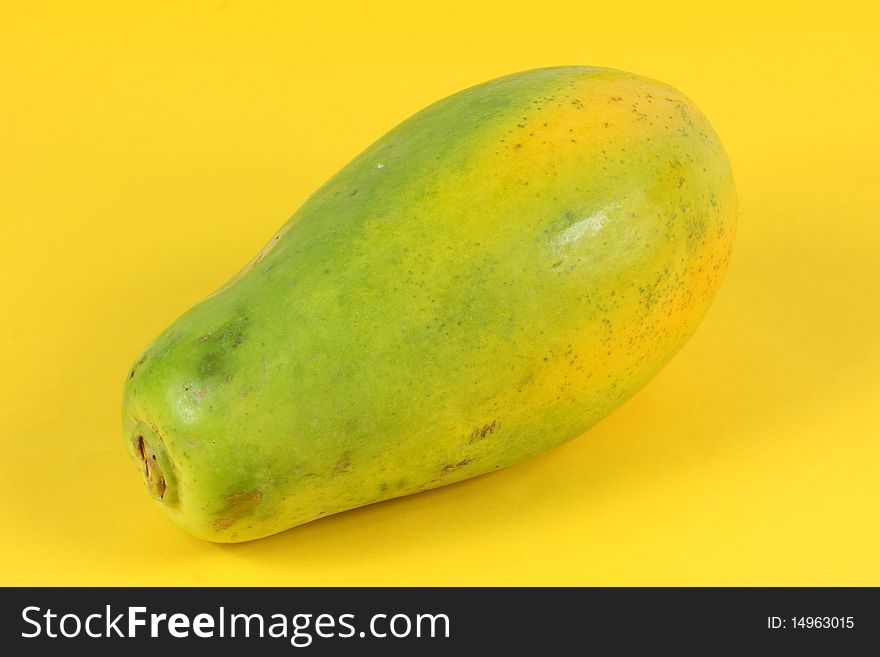 Single Papaya fruit isolated on a yellow background.