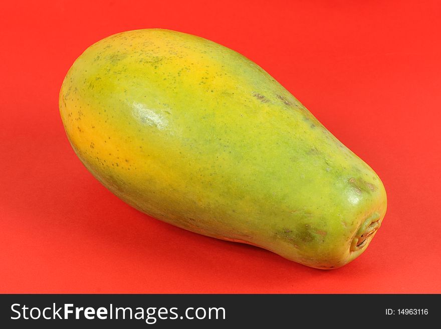 Single Papaya fruit isolated on a red background.