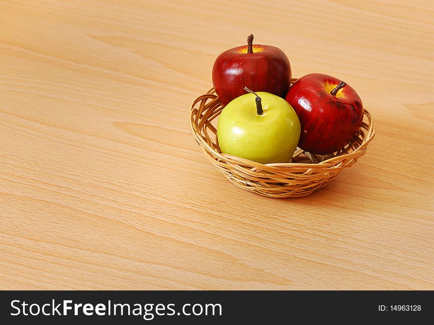 An apple basket with two red and one green apple