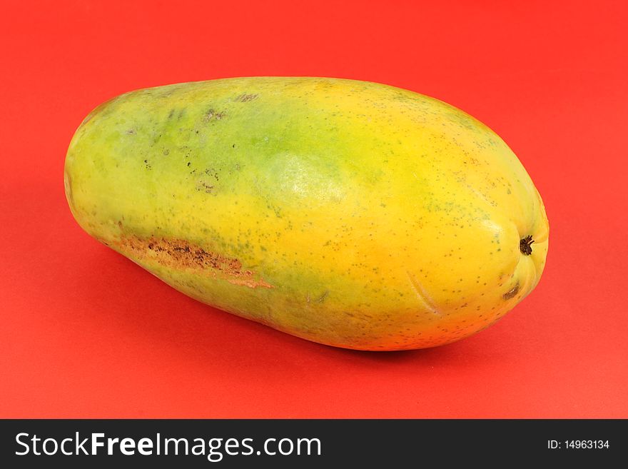 Single Papaya fruit isolated on a red background.