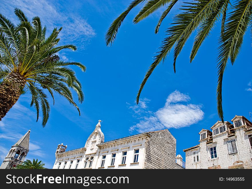 Mediterranean architecture in city of Trogir, Croatia with palm trees and blue sky in the background