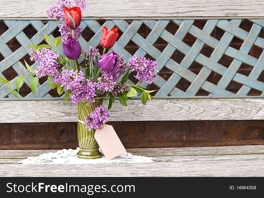 A vase of fresh spring tulips and lilac with gift card. A vase of fresh spring tulips and lilac with gift card