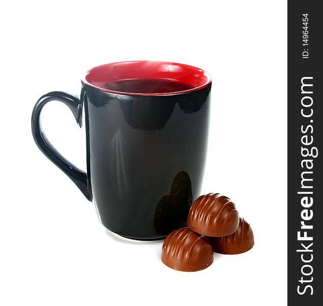 Coffee is in a black cup and chocolate candies isolated on white background