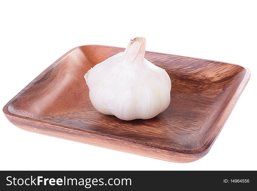 Garlic in a wooden plate on a white background.