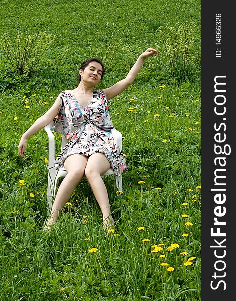 Girl resting in a chair among dandelions