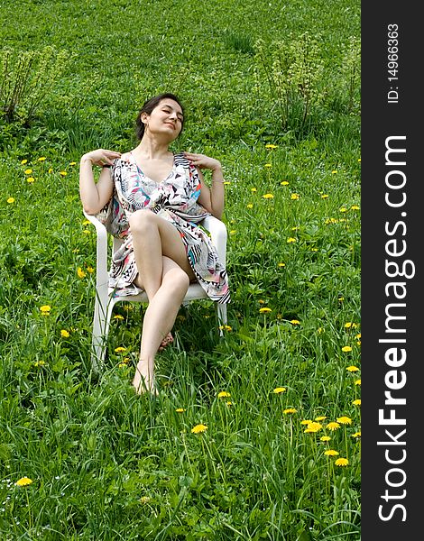 Girl resting in a chair among dandelions