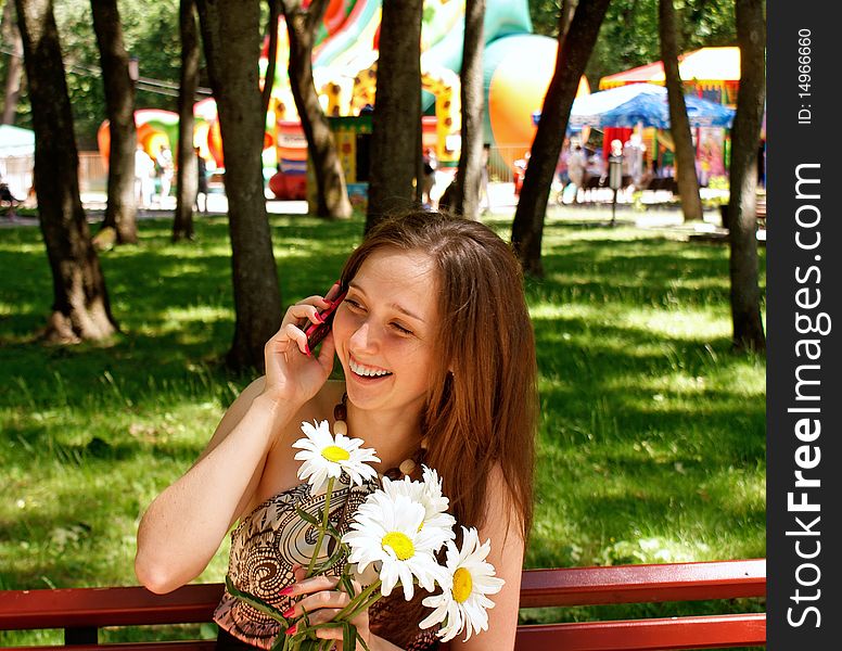 Young pretty female in solar urban park give charming smile beloved speak phone. Young pretty female in solar urban park give charming smile beloved speak phone