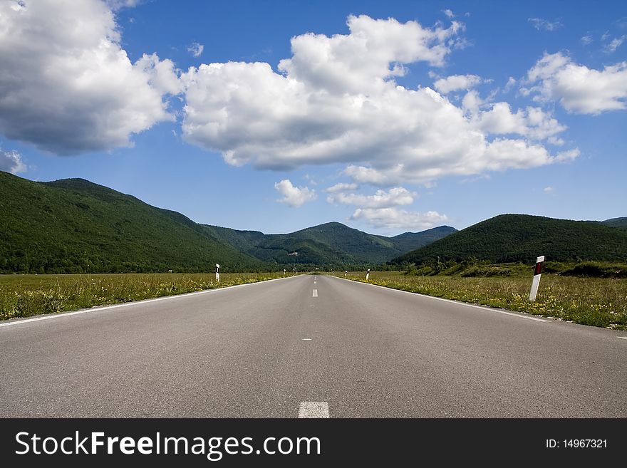 An empty road leading to the mountains in distance.